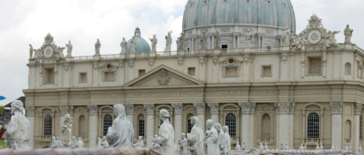 Auf dem Bild ist der Petersdom mit den davorliegenden Steinfiguren auf dem Petersdom zu sehen.